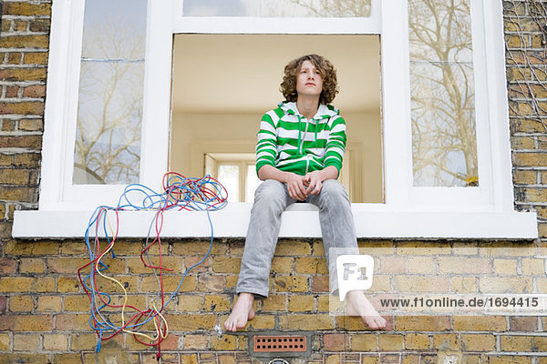 Teenage boy sat on windowsill
