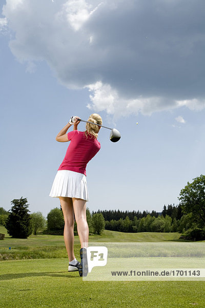 Junge Frau beim Golfen  Rückansicht