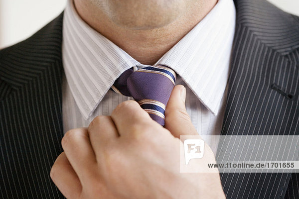 Geschäftsmann beim Anpassen der Krawatte,  Nahaufnahme