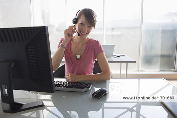 Woman working on computer,  wearing headset