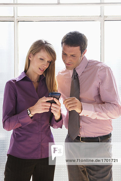 Business man and woman looking at mobile phone