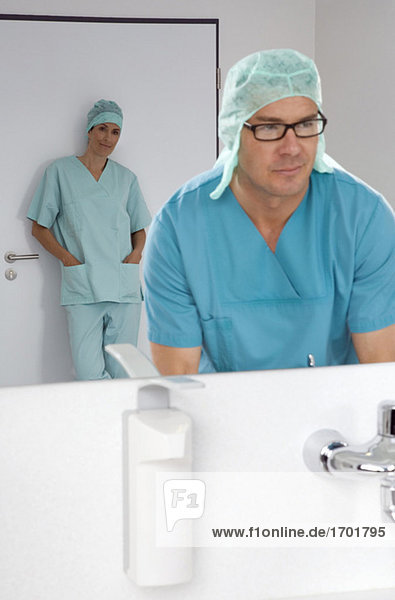 Surgeon washing his hands,  female surgeon in background