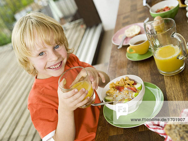 Boy at breakfast table  holding glass of juice