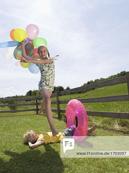 Mädchen,  hält Luftballons,  springt über Junge
