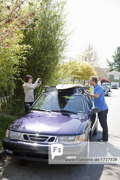 Frau fotografieren Mann mit dem Auto