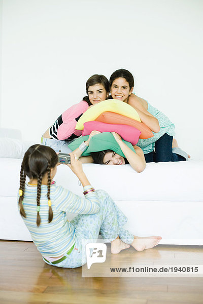 Drei junge Freundinnen posieren  während die vierte Freundin fotografiert.