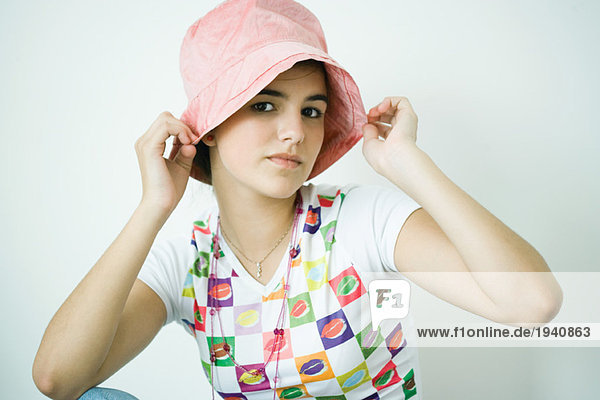 Teen girl putting on hat  portrait