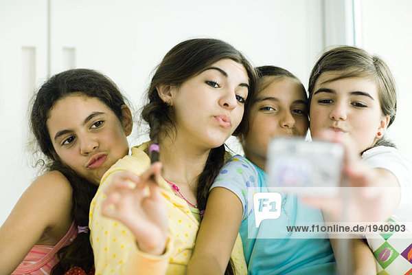 Young female friends with make-up looking at selves in hand mirror mouth