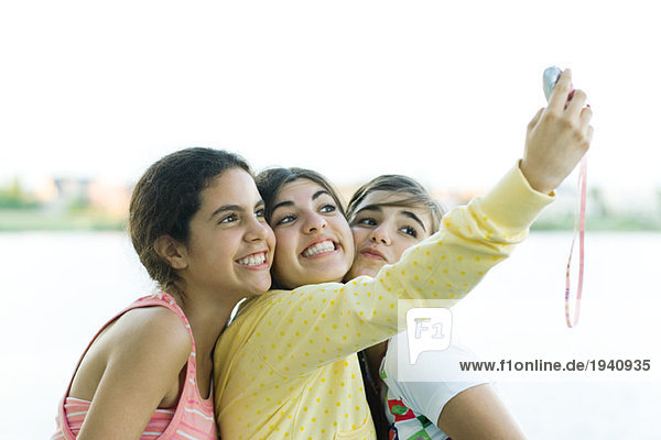 Young female friends taking photo of selves with cell phone