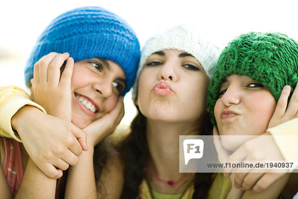 Young female friends wearing knit hats  puckering at camera