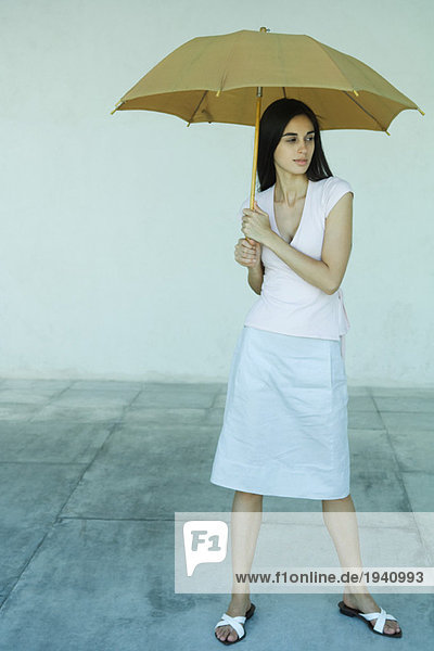 Woman standing under umbrella  full length portrait