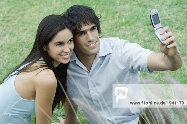 Junges Paar posiert  während der Mann das Handy zum Fotografieren hochhält.