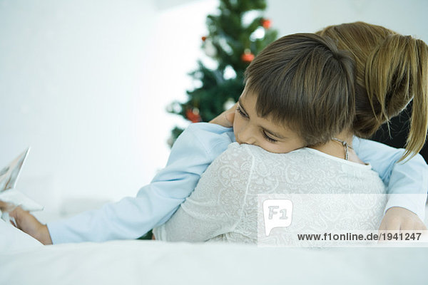 Mutter sitzt auf dem Sofa  hält den Jungen in den Armen  Weihnachtsbaum im Hintergrund  Junge hält den Stern