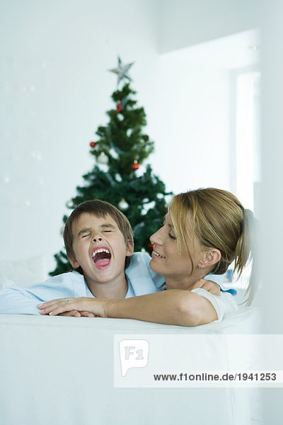 Junge und Mutter auf Sofa  Junge schreiend  Weihnachtsbaum im Hintergrund