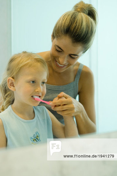 Frau hilft dem kleinen Mädchen beim Zähneputzen