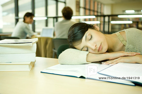 Junge Frau in der Universitätsbibliothek  Kopf an Arm  schlafend