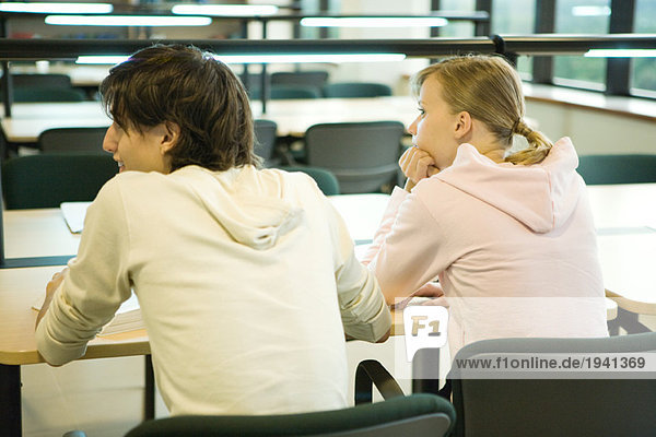 Studenten sitzen in der Bibliothek  Rückansicht
