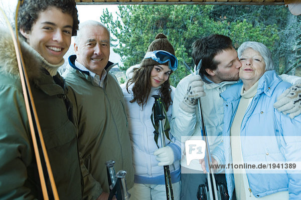 Gruppe von Skifahrern  junger Mann küsst Seniorin auf Scheck  Portrait