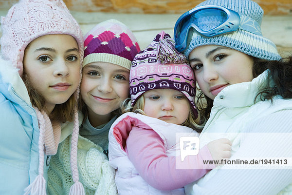 Drei Mädchen mit Kleinkind  alle mit Wintermänteln und Hüten  Portrait