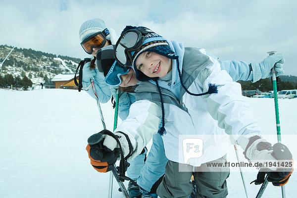 Young skiers on snow  leaning to side and smiling at camera  portrait
