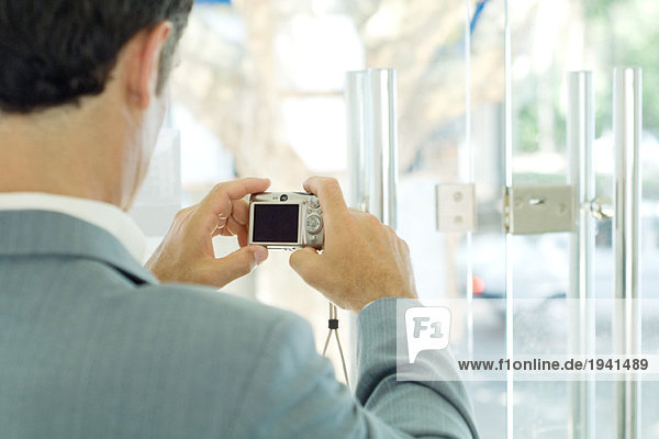 Man taking photo of lock on glass door  focus on digital camera