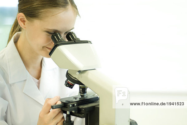 Junge Wissenschaftlerin beim Blick durchs Mikroskop