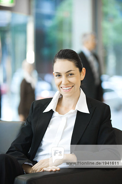Junge Geschäftsfrau sitzend  lächelnd vor der Kamera  Porträt