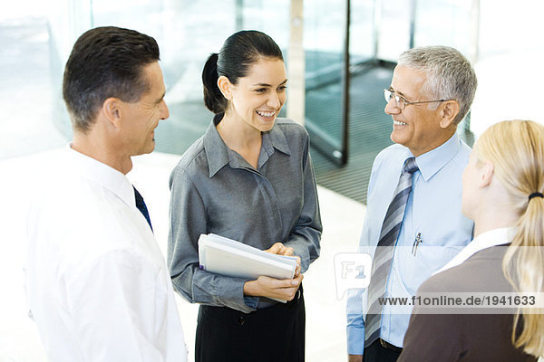 Business associates standing in lobby  smiling at each other  chatting