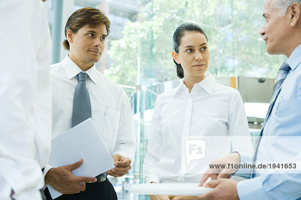 Business associates standing together  discussing  one pointing at file