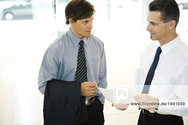 Two businessman looking at each other  discussing  one holding document