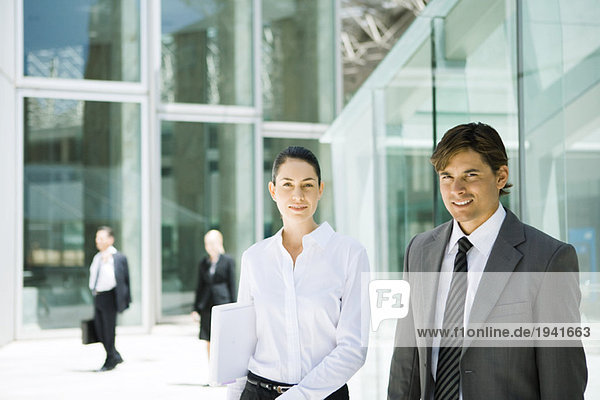 Two young business associates smiling at camera  waist up  portrait