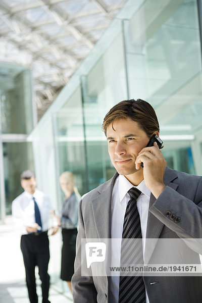 Young businessman using cell phone  looking away  portrait
