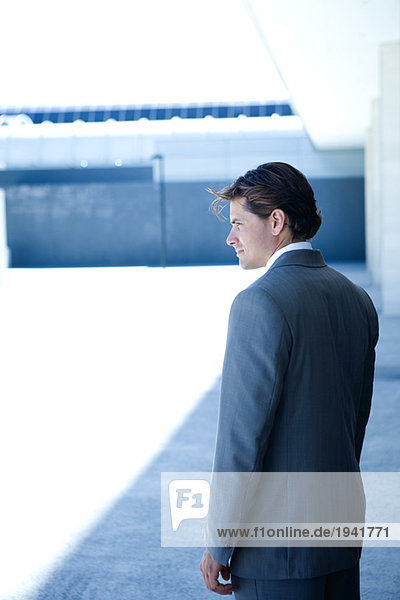 Young businessman standing  looking away  three quarter length