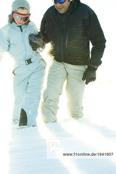 Father and daughter walking in snow together  holding hands  cropped view