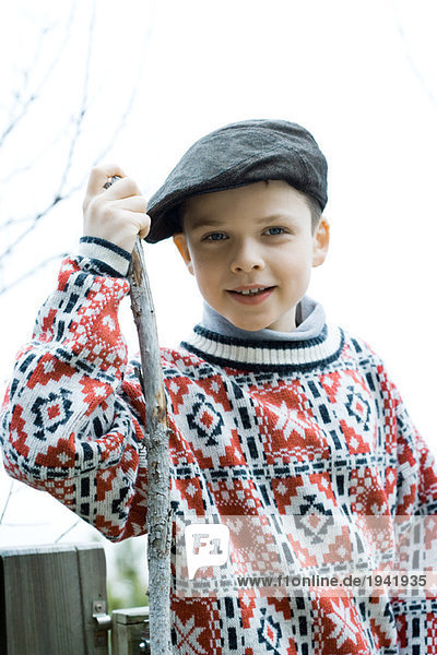 Boy wearing traditional sweater and cap  holding hiking stick