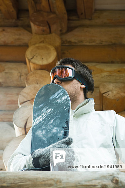 Young man holding snowboard  low angle view