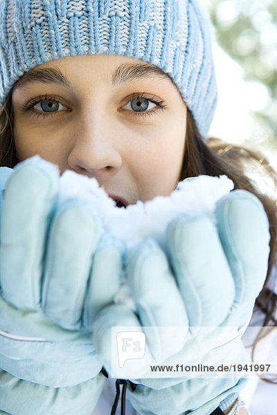 Teenagermädchen isst Schnee aus Handschuhen  schaut in die Kamera  Nahaufnahme