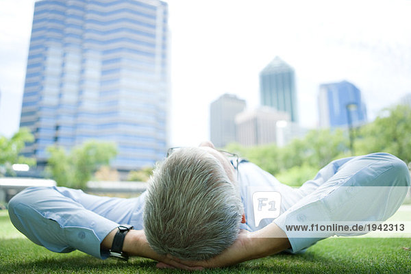 Businessman lying on grass  hands behind head