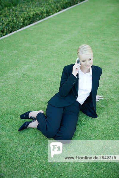 Geschäftsfrau auf Rasen sitzend  mit dem Handy  hohe Blickwinkel