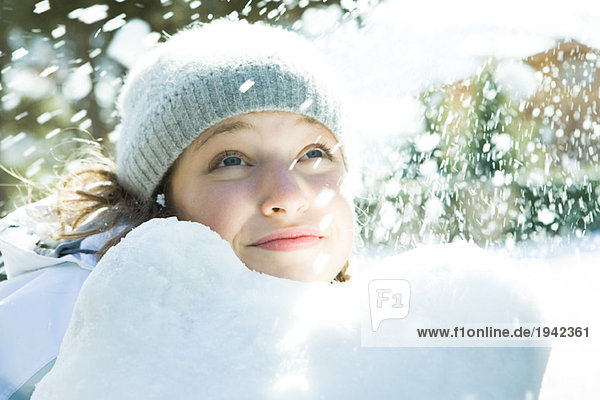 Teenage girl looking up at snow  smiling  portrait