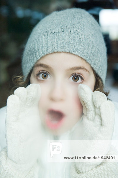 Mädchen atmet am Fenster,  gekleidet in Winterkleidung,  Blick in die Kamera,  Porträt