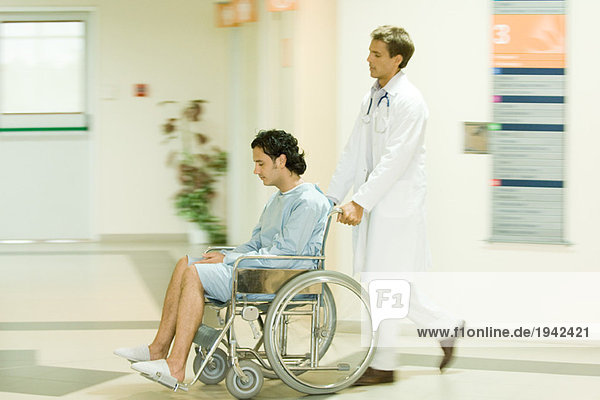 Männlicher Arzt schiebt Mann im Rollstuhl  volle Länge
