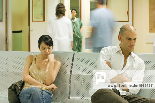 Erwachsene sitzen im Wartezimmer des Krankenhauses und schauen weg.