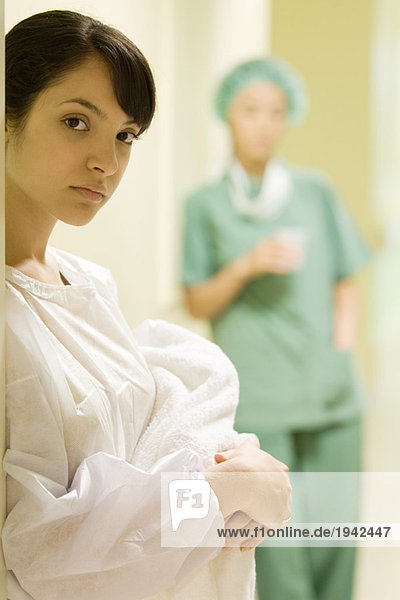 Junge Frau mit neugeborenem Baby  Blick in die Kamera  Arzthelferin im Hintergrund