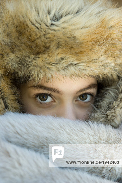 Preteen girl  wearing fur hat  looking over fur blanket  close-up