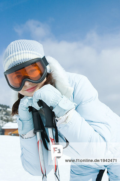 Teenagermädchen lehnt sich an Skistöcke  lächelt in die Kamera