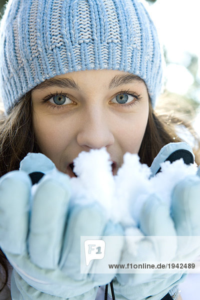 Teenagermädchen frisst Schnee aus den Händen  schaut in die Kamera