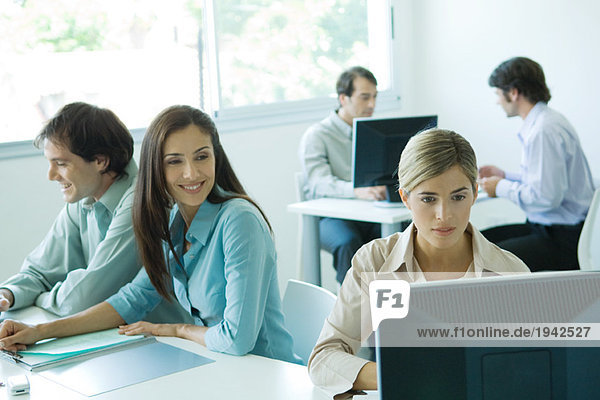 Businesswomen in office  using computer  businessmen in background
