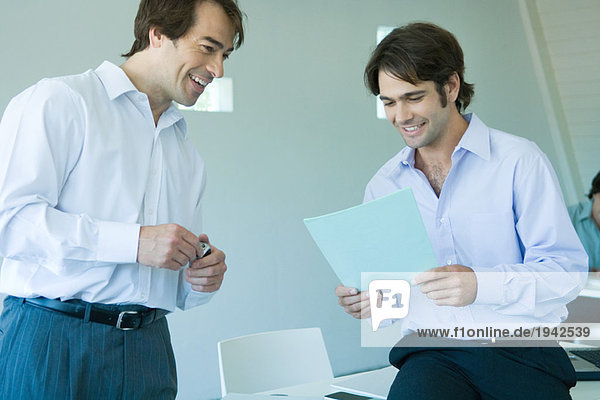 Two businessmen looking at document  smiling