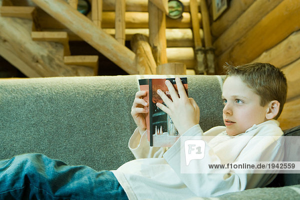 Junge auf Couch liegend  Lesebuch